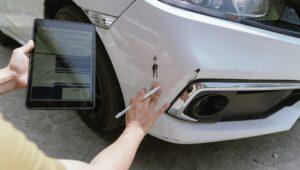 A car insurance adjuster is looking at the damage in a car accident.