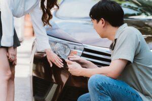 A man and a woman evaluating the damage of a minor car accident.